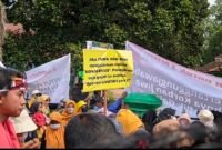 Seorang peserta aksi membawa poster bertuliskan “Jika TNWK tidak mampu menjalankan makna konservasi, pulangkan saja gajah ke habitat asalnya” saat unjuk rasa warga desa penyangga hutan di Balai Taman Nasional Way Kambas, Lampung Timur, Selasa (13/1/2026)./Hadi Jakariya