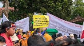 Seorang peserta aksi membawa poster bertuliskan “Jika TNWK tidak mampu menjalankan makna konservasi, pulangkan saja gajah ke habitat asalnya” saat unjuk rasa warga desa penyangga hutan di Balai Taman Nasional Way Kambas, Lampung Timur, Selasa (13/1/2026)./Hadi Jakariya