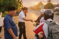 Ketua HMNI Lampung Timur Agustinus Trihandoko, dan Ketua IWO Lampung Timur, saat membagikan takjil kepada para pengendara yang melintas./Hadi Jakariya