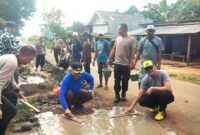 Suasana saat polisi dan warga bahu membahu perbaiki jalan di Sriminosari, Labuhan Maringgai pada Jumat pagi (15/5)./ Jahri