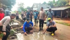Suasana saat polisi dan warga bahu membahu perbaiki jalan di Sriminosari, Labuhan Maringgai pada Jumat pagi (15/5)./ Jahri