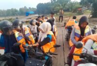 Para pelajar yang menyeberangi sungai Way Bungur mengenakan pelampung dengan didampingi polisi./Ist