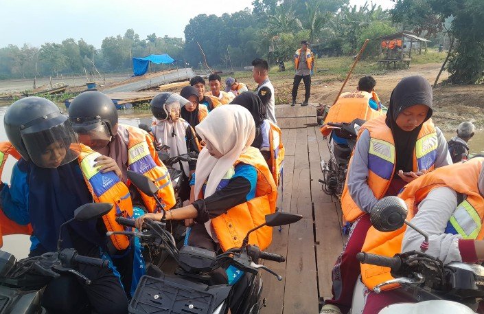 Para pelajar yang menyeberangi sungai Way Bungur mengenakan pelampung dengan didampingi polisi./Ist