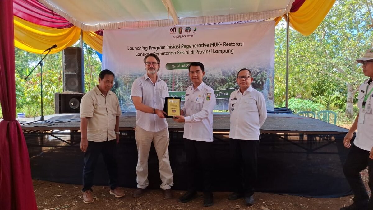 Keterangan Foto:Perwakilan PT Olam Food Ingredients (OFI) bersama Pemerintah Provinsi Lampung menyerahkan cendera mata usai peluncuran Program Inisiasi Regeneratif MUK–Restorasi Lanskap Perhutanan Sosial di Desa Sri Josari, Kecamatan Way Jepara, Lampung Timur, Rabu (15/7/2026). Program ini bertujuan memperkuat konservasi hutan melalui perhutanan sosial dan pengembangan agroforestri berkelanjutan. (Foto: Agus S)